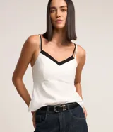 Blusa de breteles finos color blanco con escote en V y superposición contrastante en negro, confeccionada en crepé.