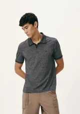 Polo de hombre color gris oscuro jaspeado, con cuello y puños de manga con ribete negro. Presenta un pequeño logo bordado en el pecho.