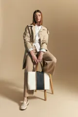 Camisa blanca de manga larga con cuello y botones frontales. Presenta detalles de volados o puntilla en los hombros y mangas abullonadas con puños anchos. La tela parece tener un sutil tejido a rayas verticales.