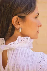 Blusa blanca de algodón con textura fruncida y detalles de broderie en cuello, mangas y ruedo.