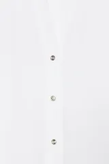 Camisa marrón de popelina con cuello solapa, escote en pico, cierre frontal con botones y mangas anchas con puños.