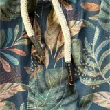 Short de baño azul con estampado de hojas en tonos verde y naranja. Cuenta con elástico en la cintura, cordón ajustable, tres bolsillos y mesh interior hipoalergénico.