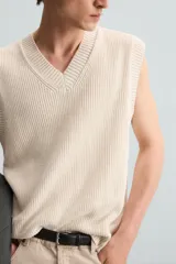 Chaleco de punto color crema con cuello en V y sisas.