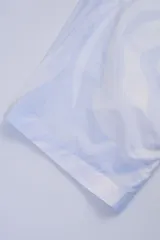 Camisa estilo camper, de fit boxy, confeccionada en popelina con estampa de mármol celeste y blanco. Tiene cuello tipo camp-collar y botones de madera.