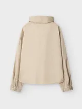 Camisa beige de algodón con cuello chimenea y cierre lateral con cuatro broches a presión. Manga japonesa con corte en la sisa en la espalda y puño con abertura y broche.