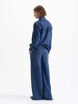 Pantalón wide leg de tiro alto color azul, confeccionado en tencel. Presenta metales dorados como detalles, bolsillos diagonales en el frente y bolsillos ojal en la espalda.
