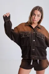 Campera de denim marrón con efecto degradado, corte boxy, cuello camisero, cierre frontal con botones metálicos, mangas largas con puños abotonados, dos bolsillos frontales con solapa y parche con logo en el frente.