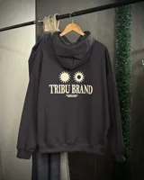 Canguro oversized color gris oscuro con capucha y estampado en la espalda que dice "TRIBU BRAND" y "THE JOURNEY CONTINUES SUMMER VOLUME II" junto a dos soles.