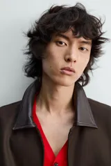 Cazadora de algodón con estructura canvas, color marrón oscuro, de corte relajado. Presenta cuello solapa de cuero negro, cierre frontal con botones a presión, bolsillos de vivo en cadera y puños y bajo elásticos.