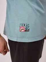 Remera de algodón con lavado, color celeste verdoso, de corte holgado (loose fit) y cuello redondo. Presenta un pequeño estampado gráfico en el pecho.