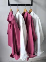 Camisa blanca de manga larga con cuello clásico y botones frontales.