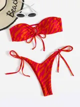 Conjunto de bikini con estampado abstracto en tonos naranja y fucsia. El corpiño es strapless con detalle de lazo ajustable en el centro. La bombacha es tipo tanga con tiras laterales ajustables.