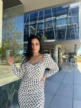 Vestido midi blanco con lunares negros, escote cuadrado, mangas largas abullonadas y corte ajustado.