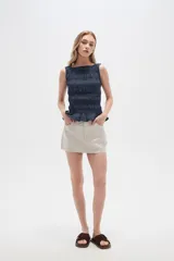 Falda mini color beige, de jean rígido, con bolsillos delanteros y traseros.