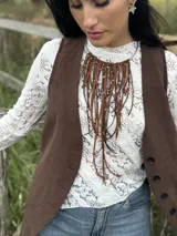 Collar con cuello rígido plateado y flecos de gamuza marrón y tiento sintético con detalles de mostacillas metálicas.