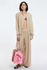 Camisa color marrón de corte holgado, con cuello clásico, mangas largas con puños abotonados y cierre frontal con botones. 