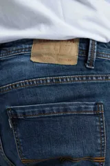 Jean azul de corte slim con detalles de desgaste y costura contrastante.