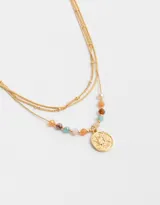 Collar corto triple dorado con cadenas de diferentes grosores. La cadena inferior tiene cuentas de colores y un dije redondo con diseño de sol.