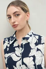 Vestido midi sin mangas confeccionado en viscosa fluida, con cuello camisero, estampado abstracto en negro y beige, y lazo para ajustar en la cintura.