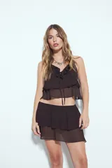 Falda corta negra con volados escalonados y cintura lisa.