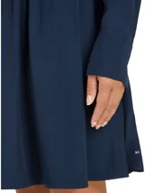 Vestido corto camisero azul marino de Tommy Hilfiger, con cuello italiano, mangas largas con puños abotonados, cinturón anudable en la cintura y logo metálico en el bajo.