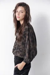 Camisa marrón con estampado abstracto en tonos cobre y negro, cuello mao y mangas largas abullonadas con puños elásticos.