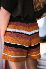 Short tejido a crochet con cintura elastizada y tiro alto, con rayas horizontales en tonos naranja, marrón, blanco y negro.