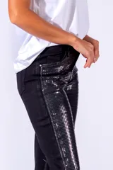 Pantalón de jean negro con apliques de lentejuelas plateadas.