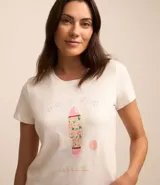 Pijama de dos piezas, compuesto por una remera blanca de manga corta con estampa de surf y un short rosa con lunares negros y cintura elástica.
