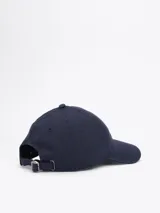 Gorra de béisbol azul marino de Tommy Hilfiger, confeccionada en tejido de espiga de algodón. Presenta diseño de seis paneles, botón en la parte superior, ojales de ventilación, hebilla de ajuste metálica en la parte trasera y logo esmaltado de Tommy en la parte delantera y la hebilla.