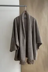 Saco de lana color marrón claro, con mangas amplias, cuello tipo bufanda con flecos y bolsillos laterales. Diseño oversize sin forro.