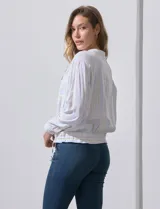 Chaqueta de lino a rayas verticales amarillas y celestes, con cuello a la base, abertura central con botones, bolsillos delanteros y ruedo con jareta de ajuste.