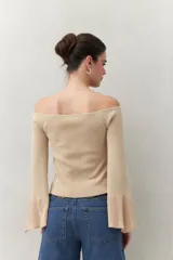 Top tejido color beige con escote off-shoulder y mangas largas acampanadas.