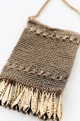 Bolso mini tipo saco confeccionado con hilo metalizado color dorado en forma de malla. Detalle de flecos metálicos labrados. Asa tipo cordón metálica.