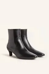 Bota corta de cuero vacuno con estampado animal print serpiente en tonos blanco y negro, con puntera fina y cierre trasero. Tiene taco chupete y suela de cuero.