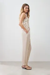 Pantalón de lino color beige con cintura elastizada con cordón ajustable, corte recto y pespuntes verticales al frente.