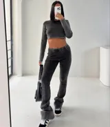 Conjunto deportivo gris oscuro compuesto por un crop top de manga larga y un pantalón acampanado con costuras verticales al frente.