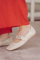 Chatitas tipo Mary Jane de charol negro con punta redondeada y tira sobre el empeine con hebilla metálica plateada.