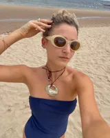 Collar con dije dorado en forma de concha marina y cordón marrón de seda natural.