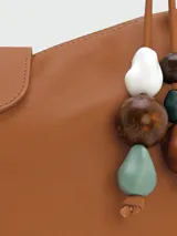 Bolso hobo de cuero color marrón, con asa corta y cierre con solapa y botón a presión.