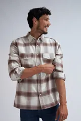 Camisa de manga larga con diseño de cuadros en tonos beige y marrón, con bolsillos delanteros y botones a presión.
