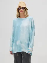 Buzo de algodón con efecto tie-dye en tonos celeste y blanco, de corte holgado y largo por debajo de la cintura, con puños acanalados.