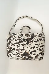 Bolso tipo tote bag con estampado de cebra en tonos beige y blanco. Tiene doble asa corta y correa larga para colgar del hombro.
