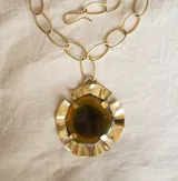 Collar con cadena de eslabones grandes color dorado y dije colgante circular con borde de bronce y centro de piedra ágata color marrón.