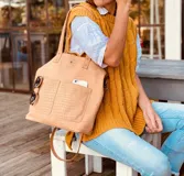 Bolso tipo tote de cuero sintético color beige con textura tipo cocodrilo. Tiene doble asa de mano y correa larga extraíble y ajustable. Cuenta con cierre principal, dos bolsillos externos y un bolsillo interno con cierre.