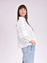 Blusa blanca de mangas largas con detalles de encaje en los puños.