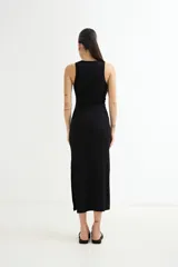 Vestido largo negro ajustado al cuerpo, sin mangas y con cuello redondo. Presenta una abertura lateral en el ruedo.