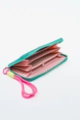 Billetera rectangular color fucsia con cierre perimetral y parche frontal negro con logo. Incluye correa de mano de cordón rosa neón y detalle de ajuste en verde lima.