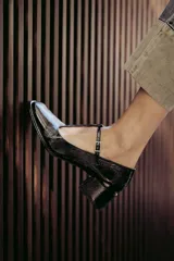 Zapatos de charol negro con diseño tipo T-bar, taco bajo cuadrado y punta redondeada.