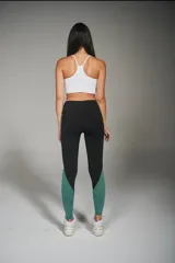 Calza deportiva larga negra con recortes laterales en blanco y verde.